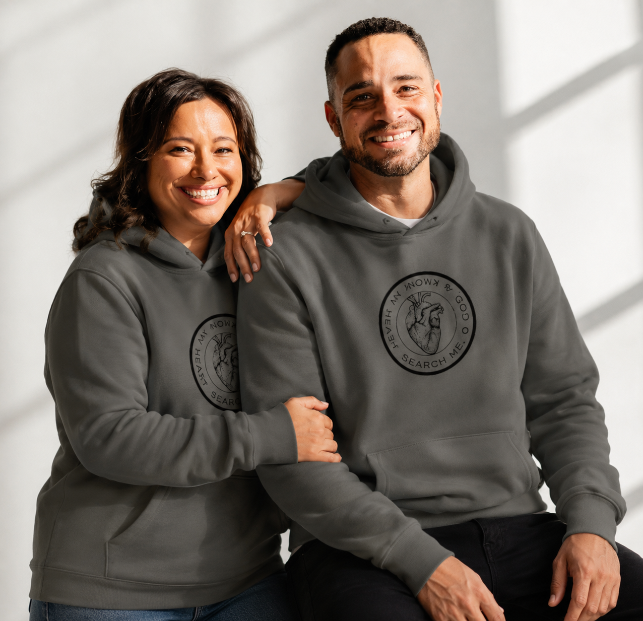 Tim and Dawna wearing Asphalt Grey hoodies with a search me on a light background